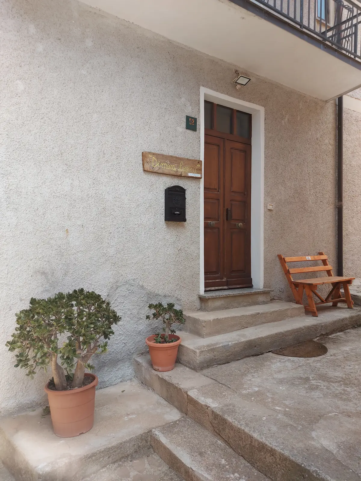 L’ingresso di Dimora Garau, con l’insegna in legno e le piante accanto alla porta